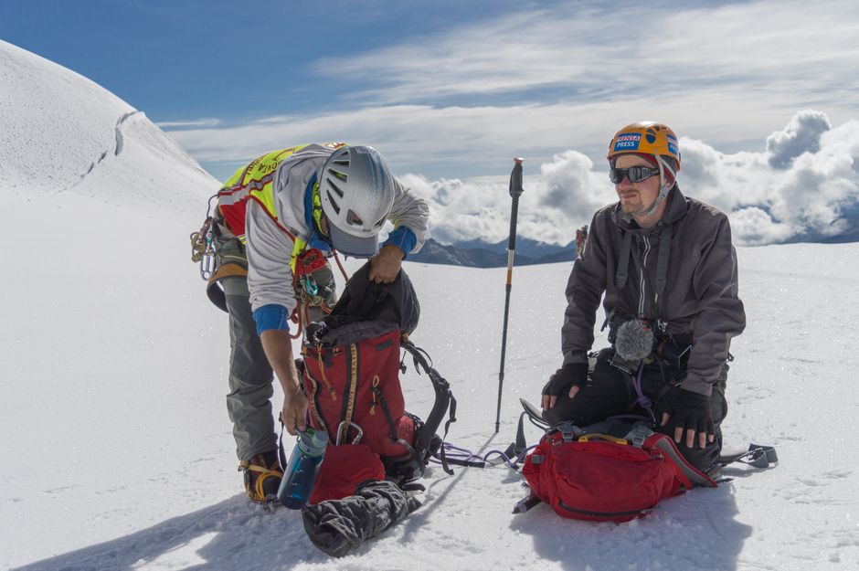 Two climbers equip themselves with gear on a snowy mountain peak in La Paz, Bolivia.